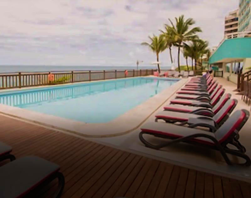 A row of chaise longue chairs next to a large oceanside pool at the Hotel Vila Gale in Salvador.