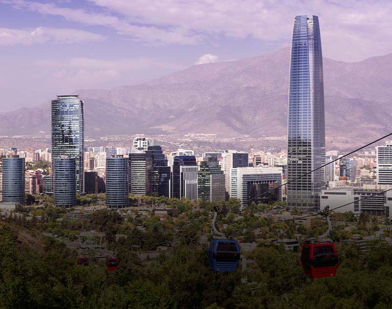Several cable cars moving through the sky with the skyline of Santiago as a backdrop.