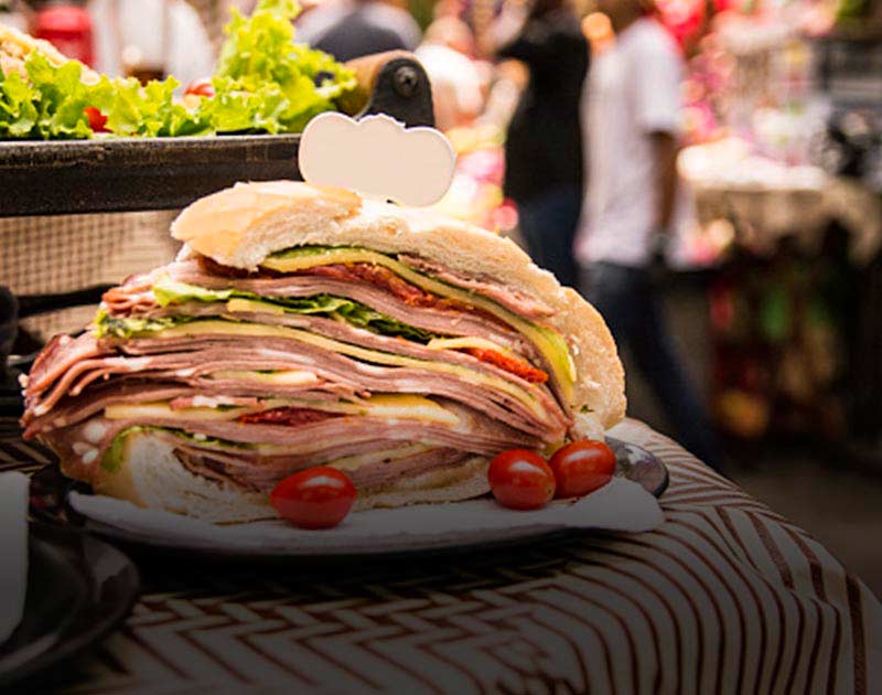 An enormous sandwich stacked with many layers of meat and cheese at a market in Sao Paulo.