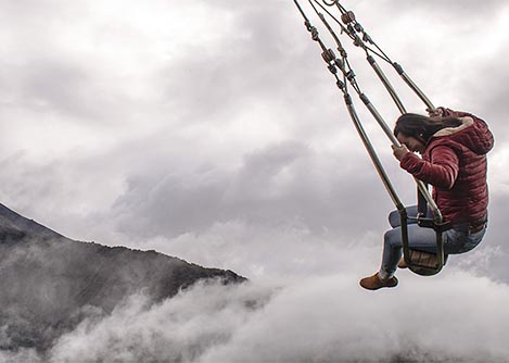 A woman swinging above the cloud forest on the Swing at the End of the World in Baños.