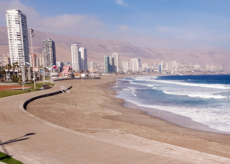 A beach and promenade lined by modern high-rise buildings in the Chilean city of Iquique.