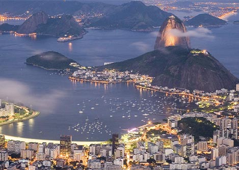 The city of Rio de Janeiro and the iconic Sugarloaf Mountain illuminated at night.