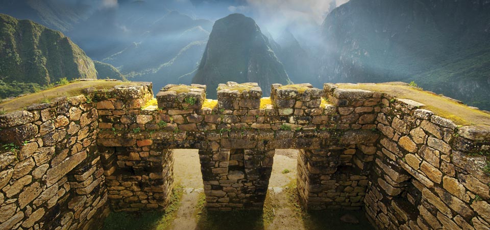 Inca-built stone walls overlooking the surrounding Andean scenery on Machu Picchu Mountain.
