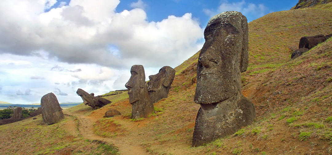 A number of the large human figures known as moais sticking out of the dirt on Easter island.