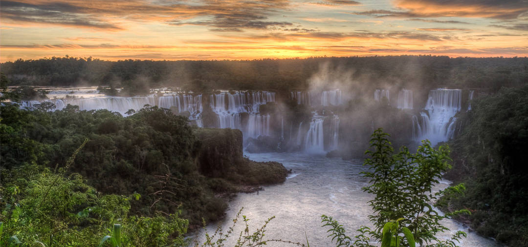The sun setting over Iguazu Falls, one of the world's largest and most beautiful waterfalls.