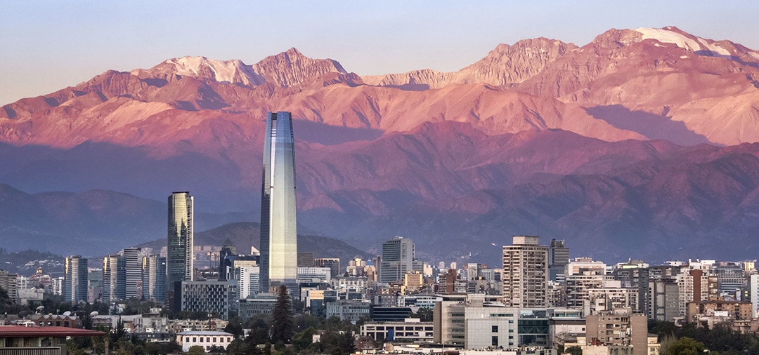 The modern buildings of Santiago overlooked by the Andes Mountains as the sun sets.