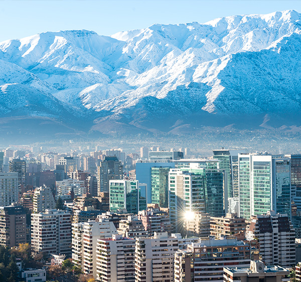 The modern skyscrapers of Santiago with the snow-capped Andes Mountains overhead.
