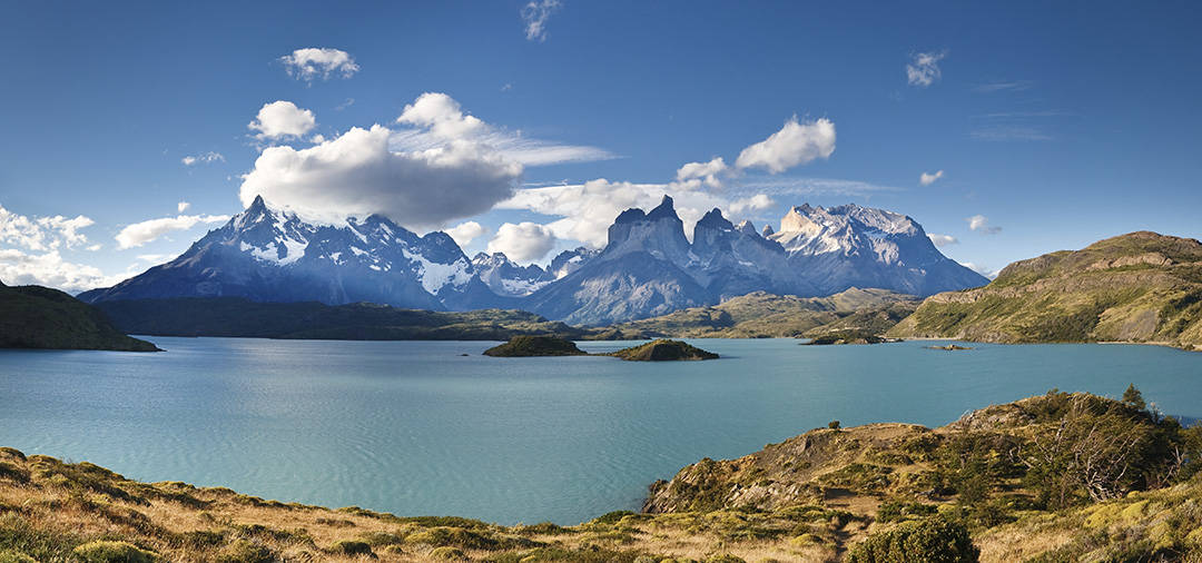 A blue lake overlooked by snow-capped peaks as well as the back of the iconic Torres del Paine.