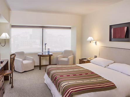 A cozy room with a bed and small table at the Almacruz Hotel and Convention Center in Santiago.