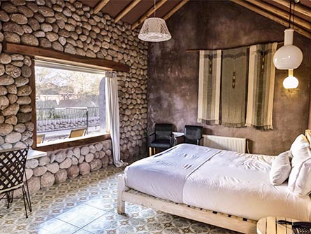 A simple but cozy room with a stone wall at the Altiplanico Hotel in San Pedro de Atacama.