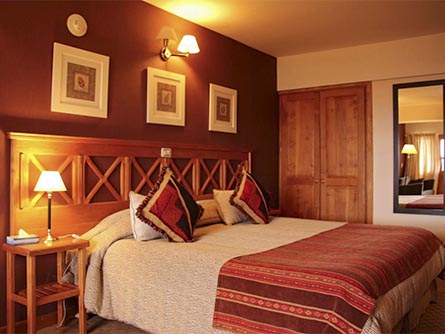 A cozy and well-decorated room with wooden furniture and red linens at Altos Ushuaia Hotel.