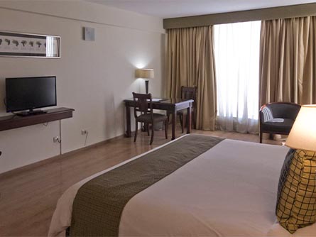 A spacious room at the Amerian Executive Hotel in Mendoza, with wood flooring and furniture.