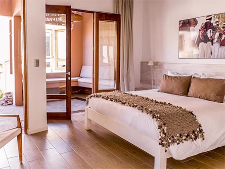 An elegant hotel room at the Casa Atacama, with glass doors leading to a second room.