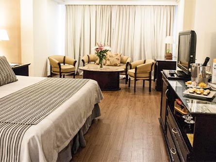 A room at the Casa Real Hotel with flowers on the table as well as food and wine on the counter.