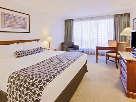A spacious room at the Crowne Plaza in Santiago with a large bed, a table and a recliner.