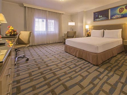 A spacious room with carpeting and some paintings on the wall at the Grand Hotel Guayaquil.