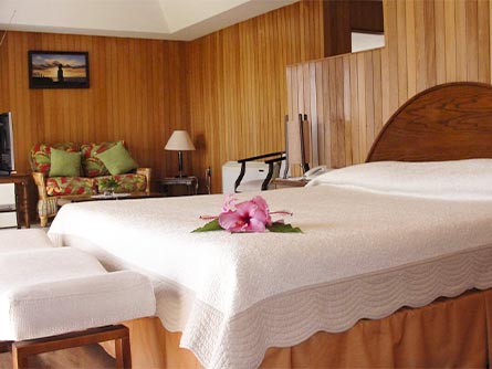 A room with wood panel walls and a bed with a flower on it at the Hotel Iorana on Easter Island.