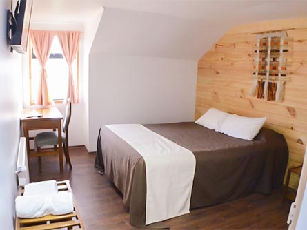 A cozy room with wood flooring, a wood wall, and a small window at the Hotel Patagonico.
