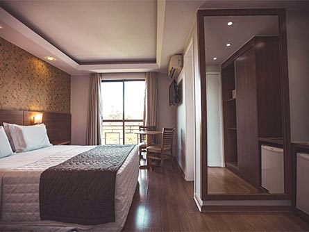 A room at the Hotel Rafain Centro near Iguazu Falls, with wood flooring and a large mirror.