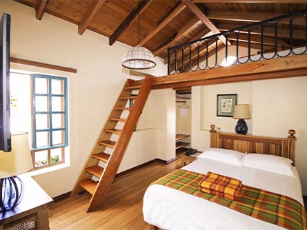 A loft-style room with wooden floors and furniture at the Hotel Vieja Cuba in Quito.