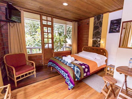 A beautiful room with wood floors and a bed with an Andean design at the Isla de Baños hotel.