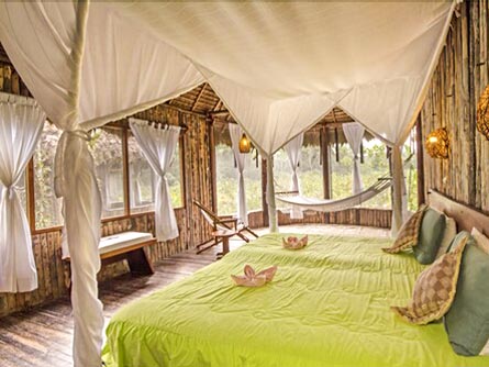 A spacious room with a large bed in a bamboo structure at the Kapawi Ecolodge & Reserve.