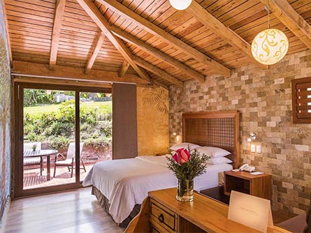 A beautiful room with stone tile walls and an outdoor terrace at the Luna Volcan Adventure Spa.
