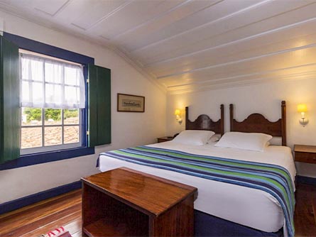 A cozy room with wood flooring and a blue and green design motif at the Pousada Porto Imperial.