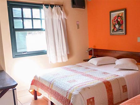 The sun shining into a simple room with an orange wall at the Pousada Villa Harmonia in Paraty.