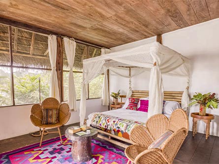 A room featuring a colorful rug and wicker and bamboo furniture at the Selina Amazon Tena.