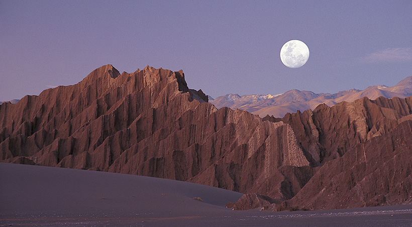 The moon shining down on the impressive rock formations of the Valle de la Luna (Moon Valley).