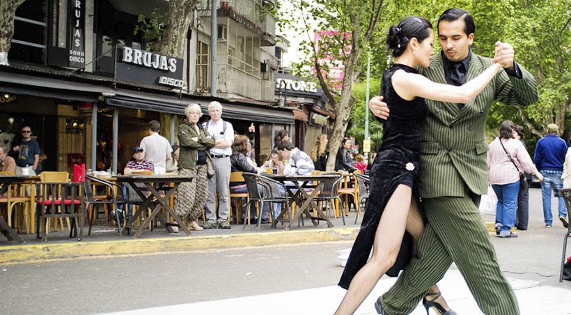 Tourists watching as a well-dressed couple dances the tango in the streets of Buenos Aires.