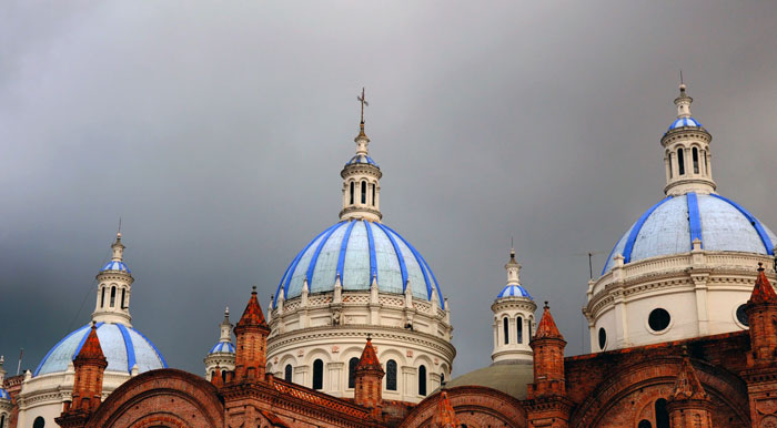 A dark and cloudy sky overlooking the blue and white domes of the New Cathedral in Cuenca.