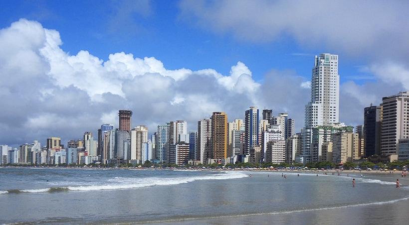 The skyline of Florianópolis overlooking the city's beaches with some beachgoers enjoying the water.