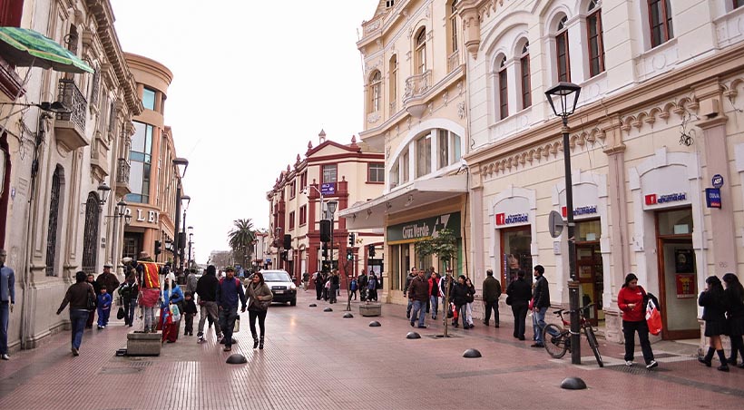 Visitors walking along a street lined with historic buildings in the historic center of La Serena.