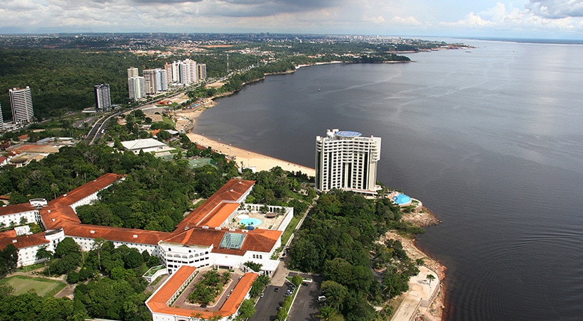 Hotels lining the waterfront, surrounded by tropical forest in the Amazonian city of Manaus.