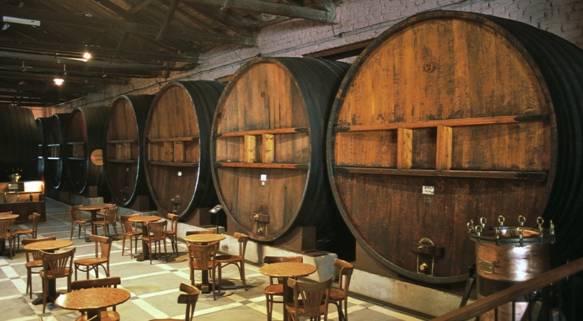 Giant wine barrels overlooking several tables in the tasting room at a Mendoza vineyard.