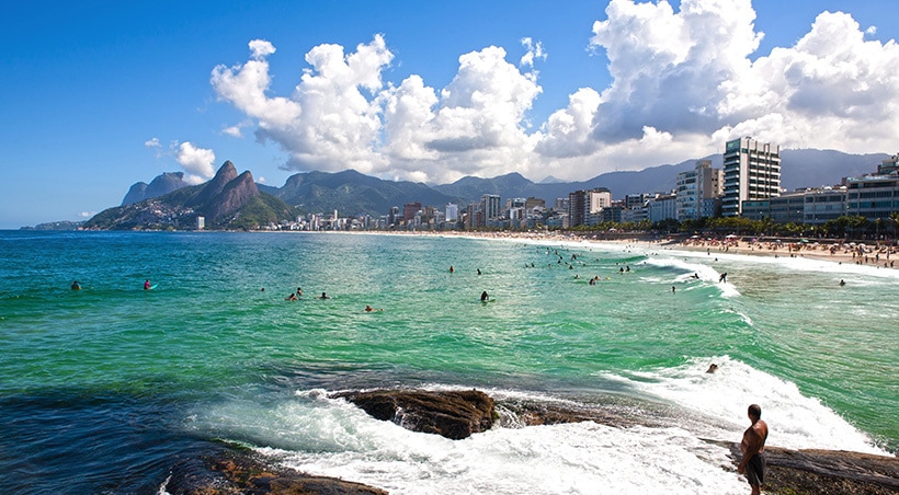 Swimmers and surfers enjoying the water on a sunny day at the beach in Rio de Janeiro.