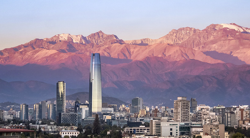 The modern buildings of Santiago overlooked by the Andes Mountains as the sun sets.