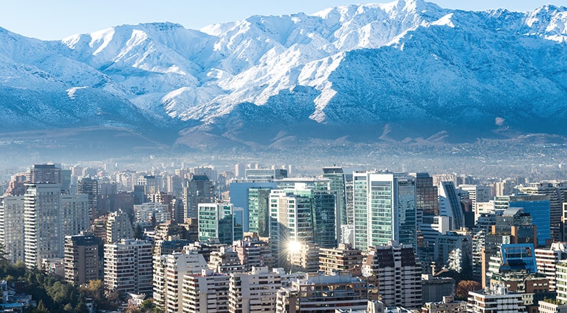 The modern skyscrapers of Santiago with the snow-capped Andes Mountains overhead.