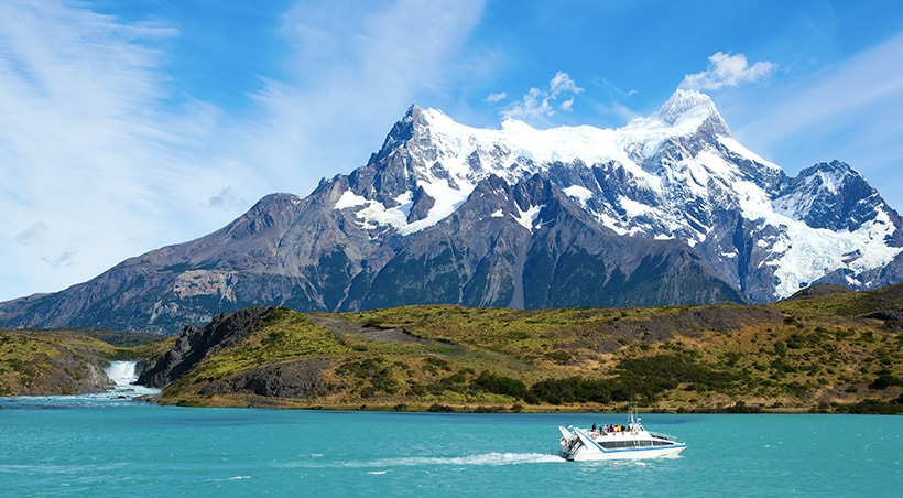 A catamaran navigating the water with mountains overhead in Torres del Paine National Park.