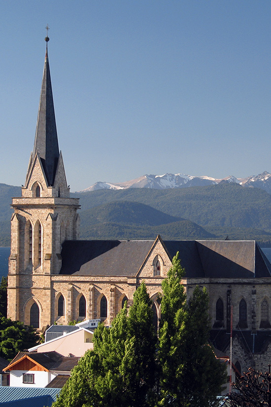 A scenic church overlooked by the snow-capped Andes Mountains in the town of Bariloche, Argentina.