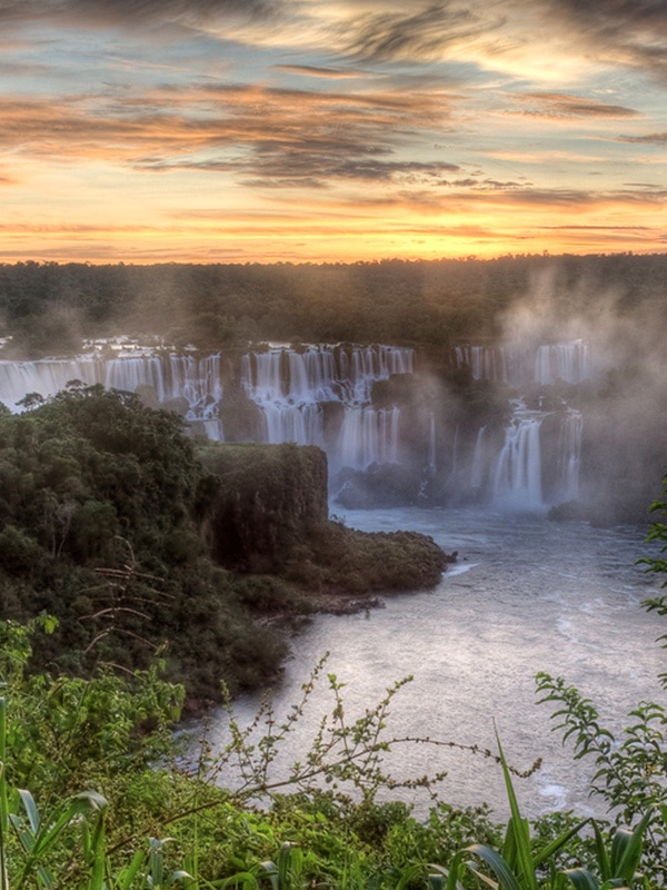 The sun setting over Iguazu Falls, one of the world's largest and most beautiful waterfalls.