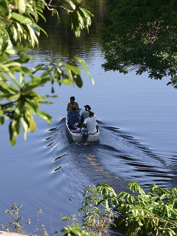 A man piloting a small motorized boat through a waterway in the Brazilian Amazon 