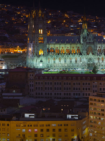 Buildings of Quito at nighttime, including the iconic Basilica of the National Vow.