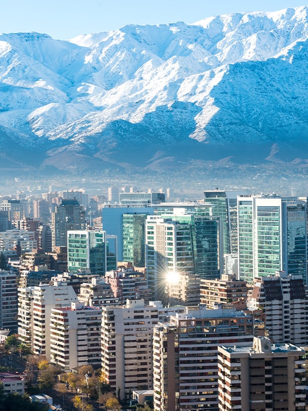 The modern skyscrapers of Santiago with the snow-capped Andes Mountains overhead.