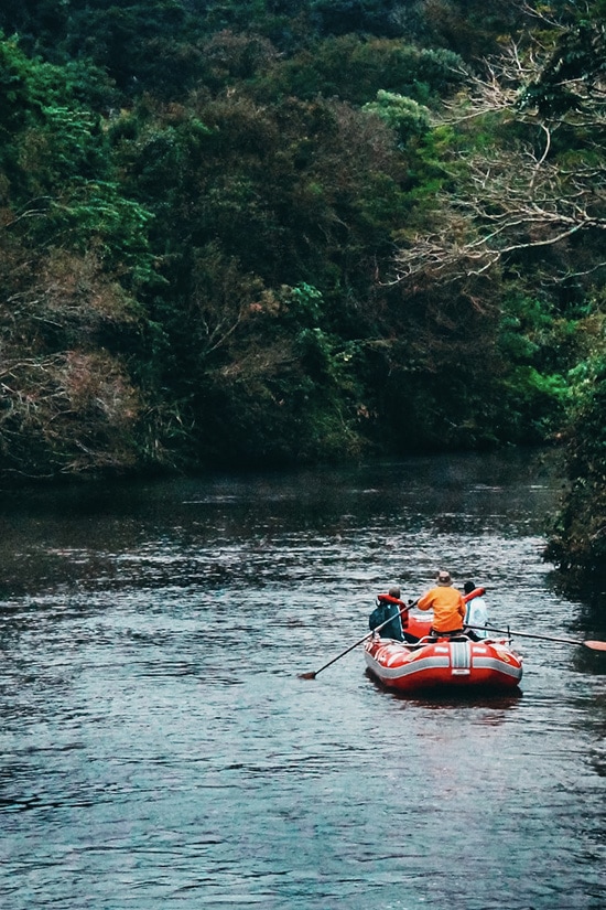 A group of visitors rafting through a waterway surrounded by jungle greenery at Iguazu Falls