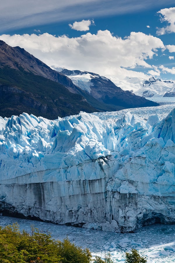 Panoramic view of the blue-tinted Perito Moreno glacier and surrounding mountains.