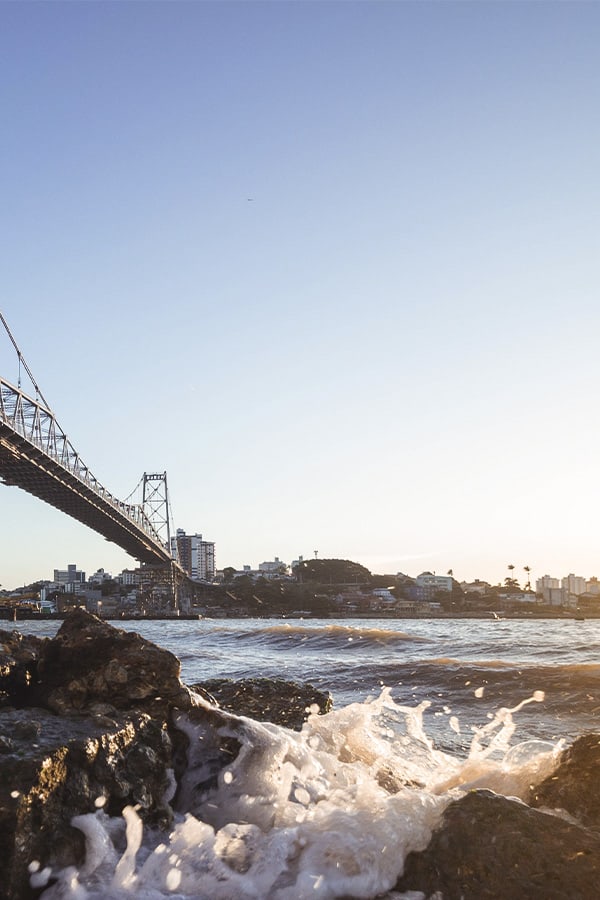 Waves splashing up onto some rocks underneath the Hercílio Luz Bridge in Florianopolis.