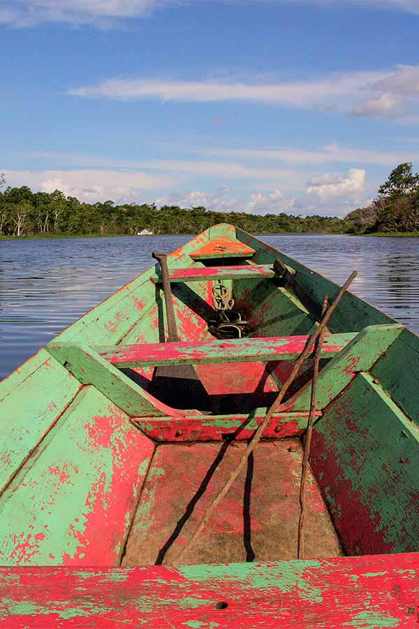 A small wooden boat floating on a river in the Amazon Rainforest near the city of Manaus.